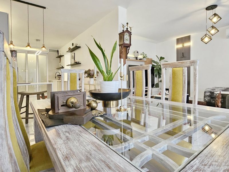 A bright open-plan living and dining area featuring modern pendant lighting, tiled floors, and a split-system air conditioner.