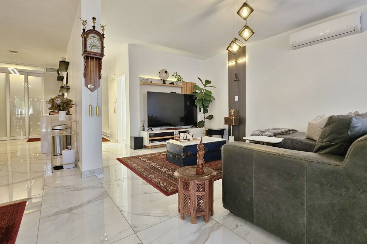 A bright and modern living room featuring polished marble-look floor tiles, decorative wall paneling, and a wall-mounted split-system air conditioner.