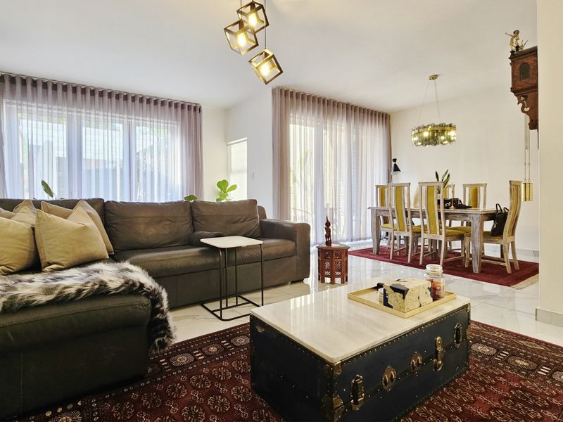 Spacious open-plan living and dining area featuring large sliding glass doors, modern tiled flooring, and contemporary lighting fixtures.