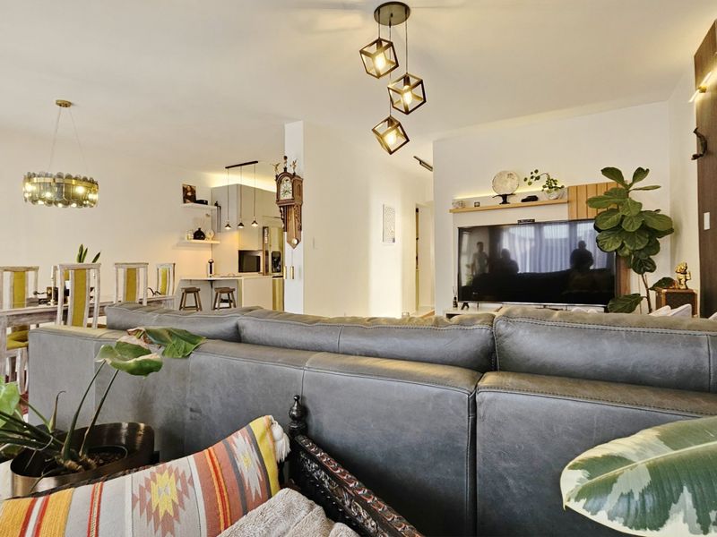 Spacious open-plan living and dining area featuring modern pendant lighting, a built-in media wall, and a functional kitchen with island seating.