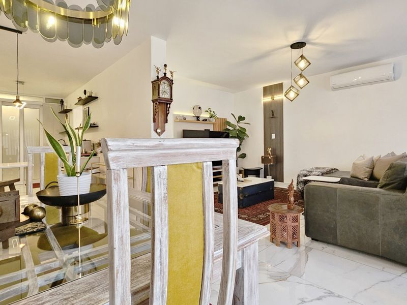 An open-plan living and dining area featuring polished marble-look floor tiles, modern pendant lighting, and a wall-mounted split-system air conditioner.