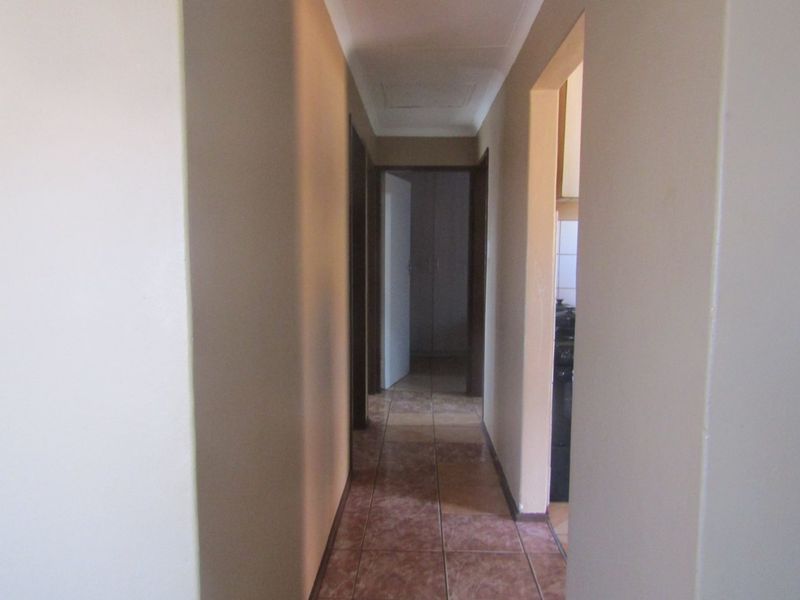 A functional interior hallway featuring tiled flooring and neutral wall finishes, providing access to adjacent rooms within the property.