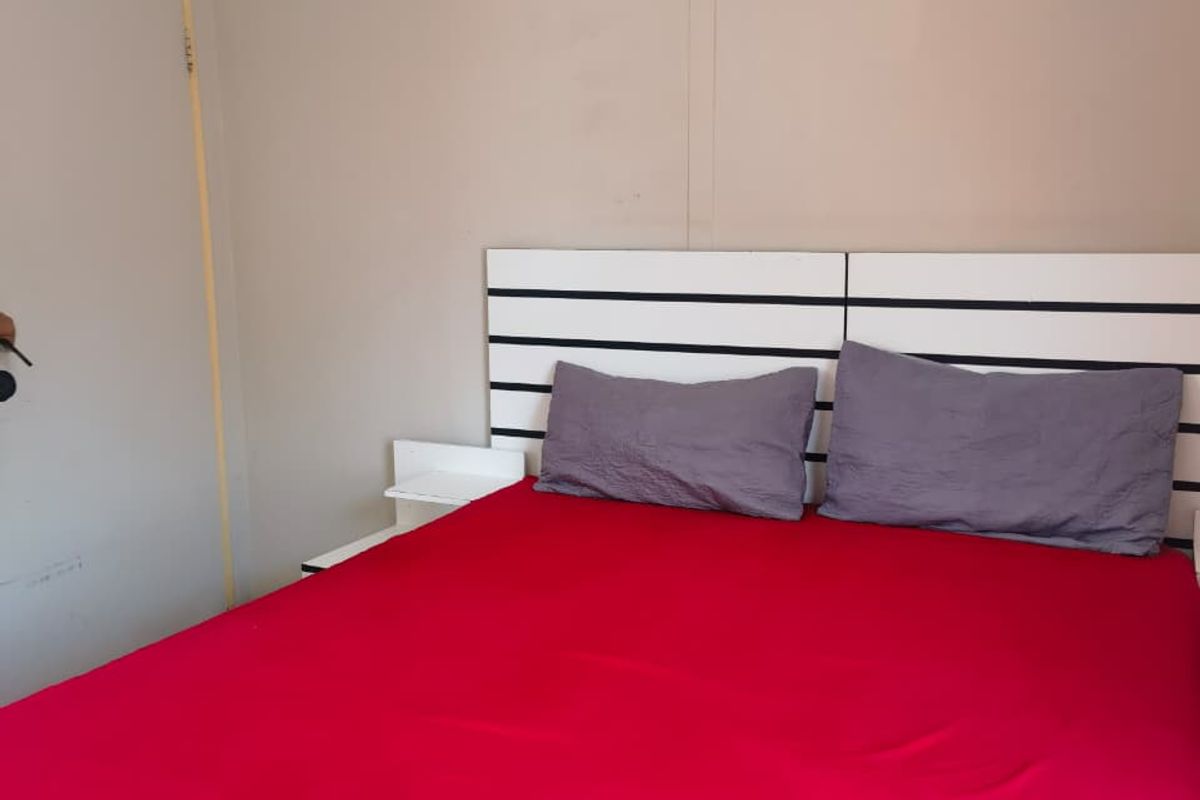 A bedroom featuring a built-in headboard and neutral wall finishes, requiring minor cosmetic updates to improve the overall aesthetic.