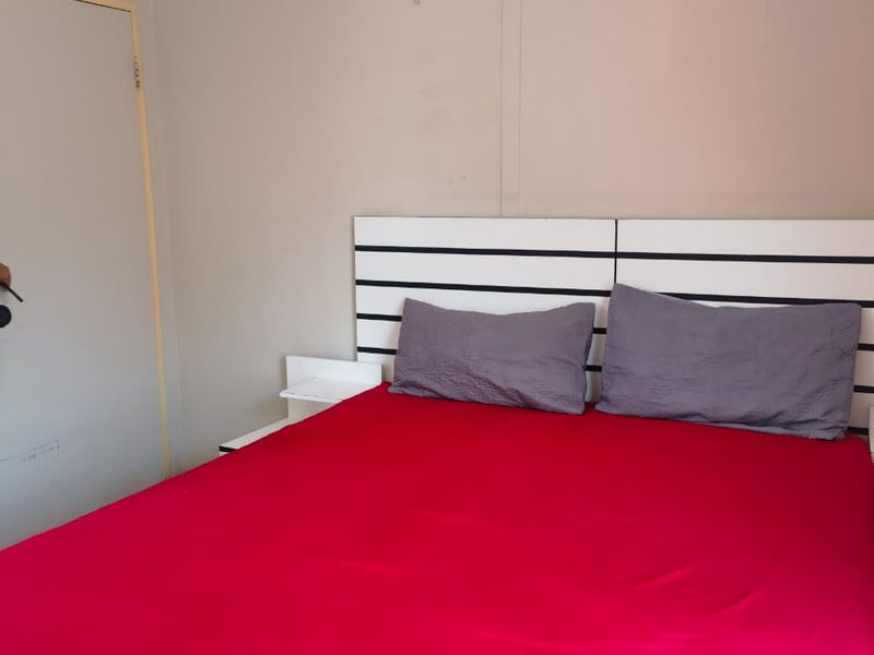 A bedroom featuring a built-in headboard and neutral wall finishes, requiring minor cosmetic updates to improve the overall aesthetic.