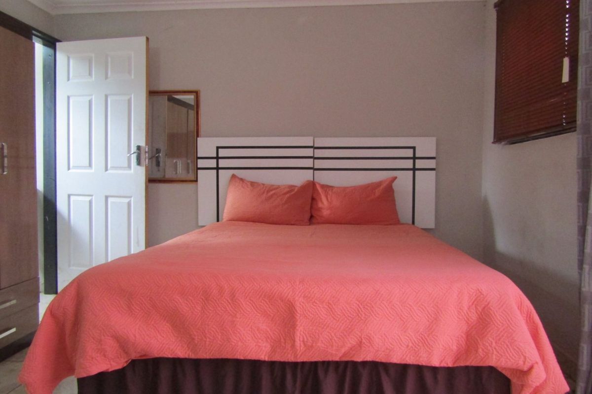 A functional bedroom featuring a built-in wardrobe and window blinds, offering a neutral base for personalization.