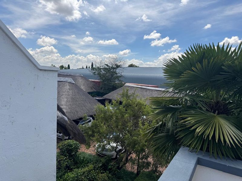 Elevated view overlooking a commercial property complex featuring multiple thatched roof structures and a large metal-roofed warehouse building.