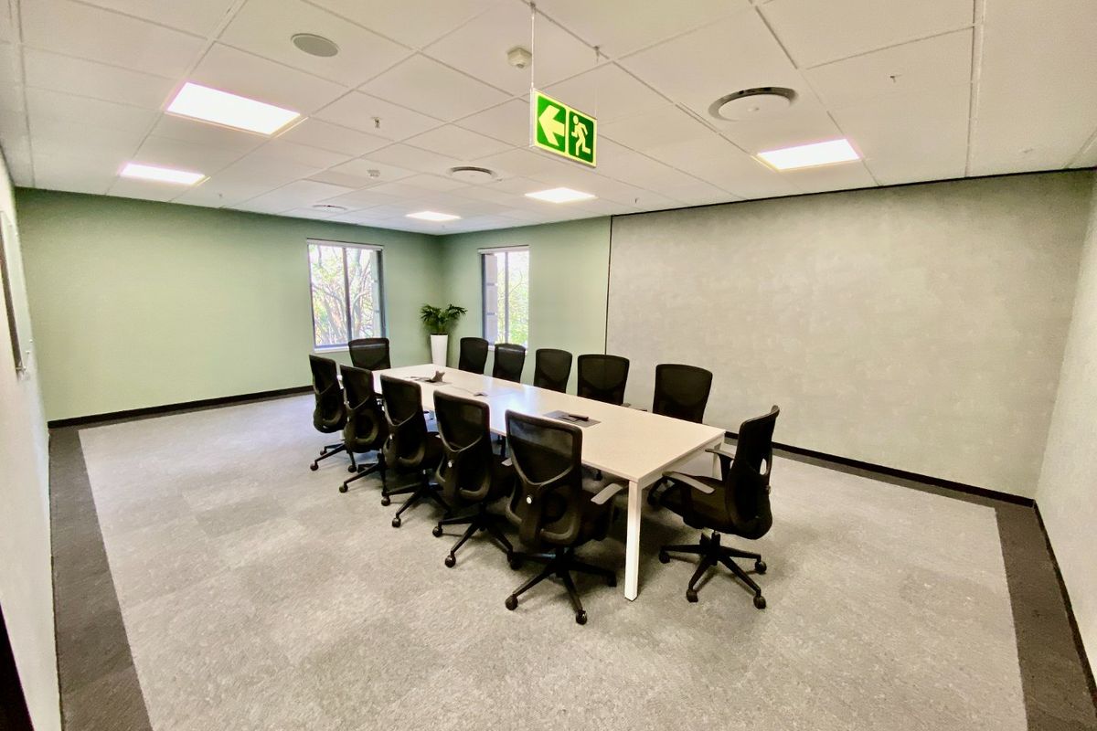 A professional commercial boardroom featuring a suspended ceiling, recessed lighting, and carpeted flooring, suitable for meetings and collaborative work.