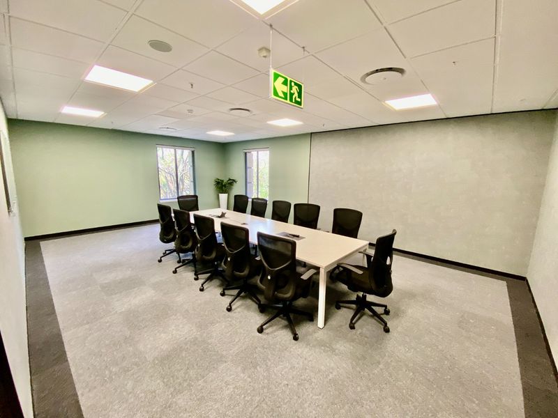 A professional commercial boardroom featuring a suspended ceiling, recessed lighting, and carpeted flooring, suitable for meetings and collaborative work.