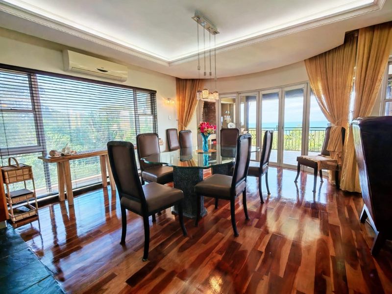 Spacious dining room featuring polished hardwood floors, recessed ceiling lighting, and large sliding glass doors that open to a balcony with scenic views.