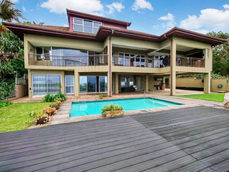 Rear exterior view featuring a swimming pool, timber decking, covered patio area, and a multi-level balcony with metal railings.