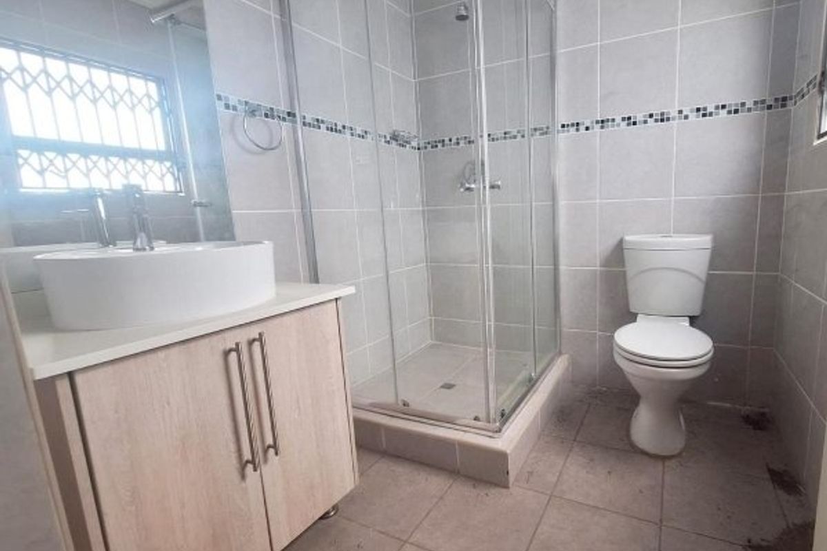 A functional bathroom featuring a glass shower enclosure, a modern vessel sink with a vanity cabinet, and a standard toilet with tiled finishes.