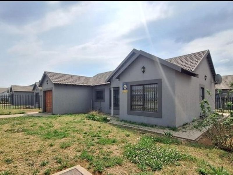 Front view of a single-story residential house featuring a tiled roof, attached garage, and security bars on windows, set within a fenced property.