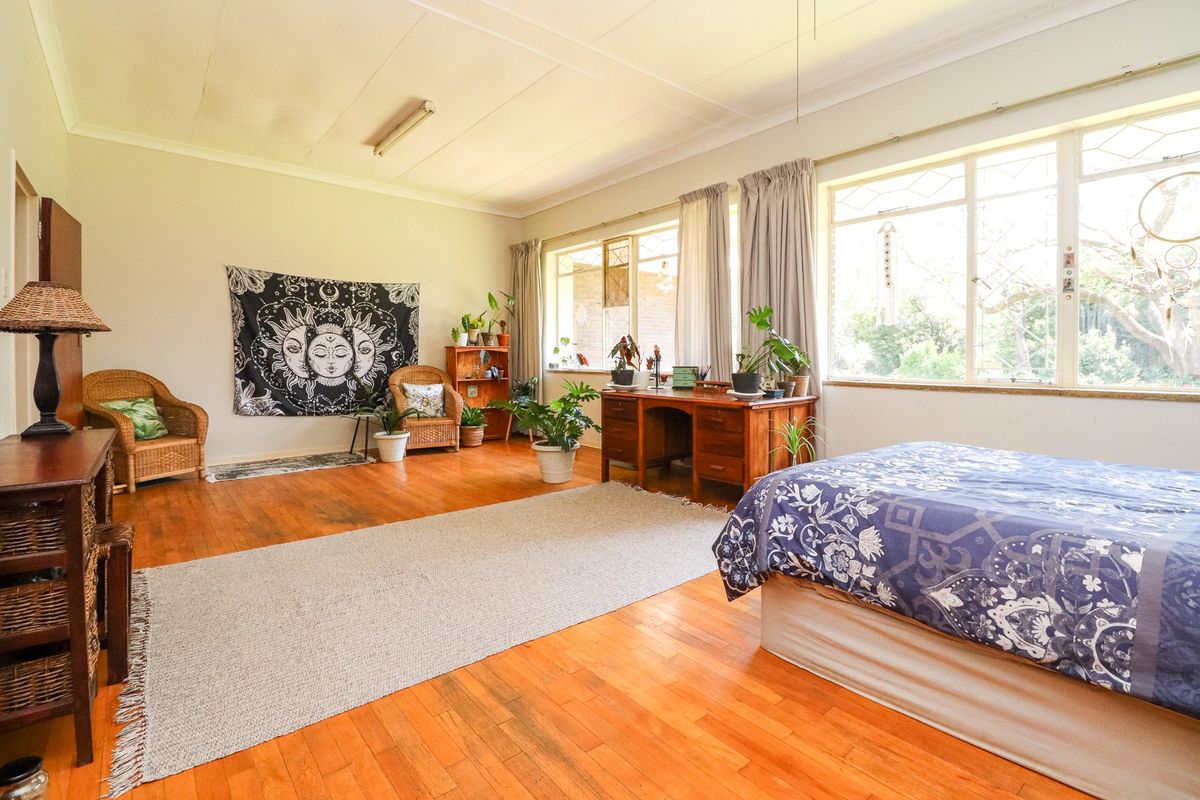 Spacious bedroom featuring original hardwood flooring and large windows that provide ample natural light.