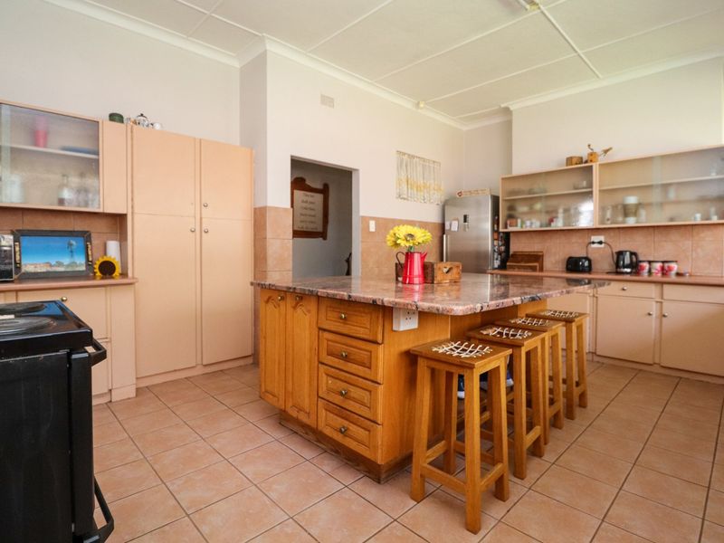 Spacious kitchen featuring a central island with granite countertop, ample built-in cabinetry, and tiled flooring throughout.