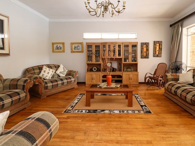 A spacious living room featuring warm hardwood flooring, crown molding, and built-in wooden display cabinetry, offering a comfortable and traditional living space.