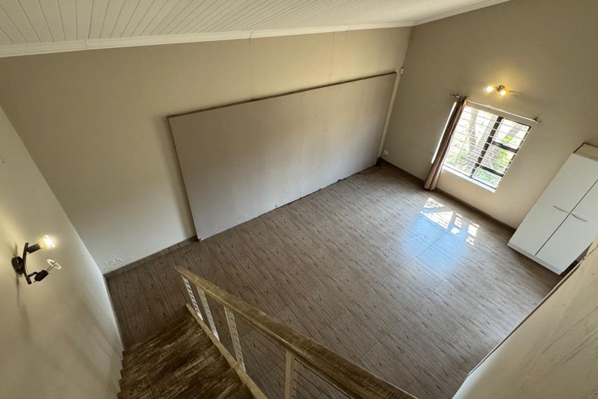 Spacious bedroom featuring wood-look tile flooring, a high tongue and groove ceiling, and a staircase leading to the upper level.