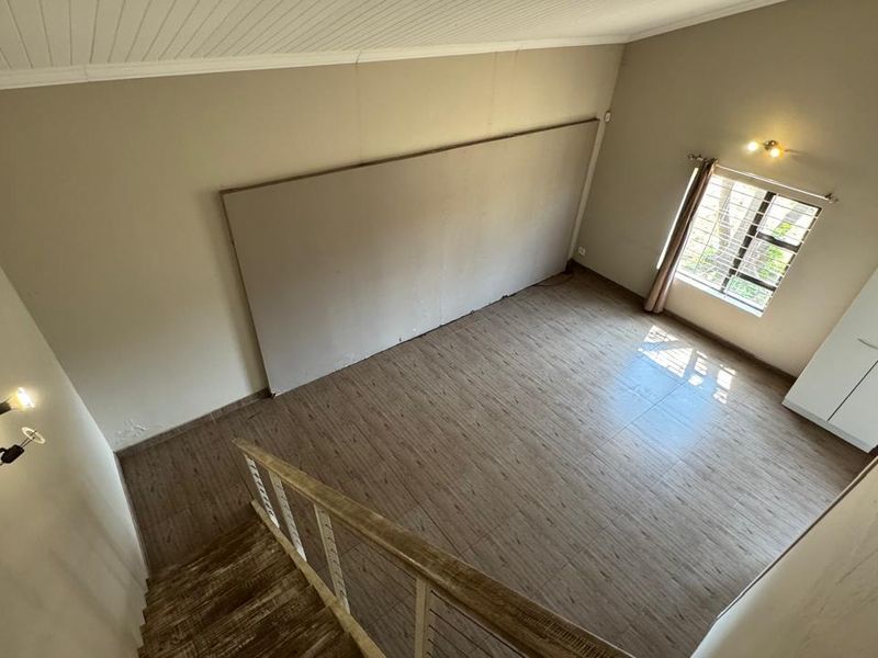 Spacious bedroom featuring wood-look tile flooring, a high tongue and groove ceiling, and a staircase leading to the upper level.