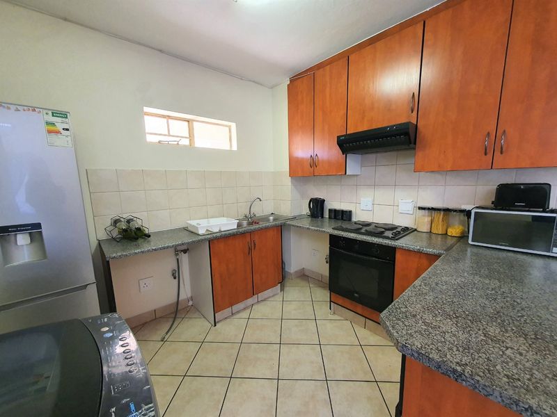 Functional kitchen featuring wood-finish cabinetry, granite countertops, tiled backsplash, and built-in oven with extractor fan.
