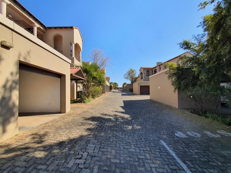A view of the paved complex driveway featuring multiple garage entrances and residential apartment building facades.