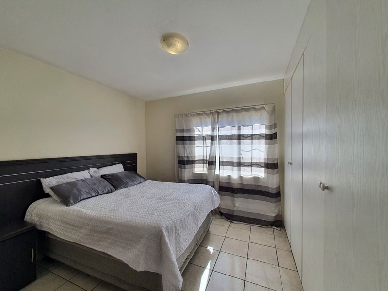 A functional bedroom featuring tiled flooring, built-in cupboards for storage, and a central ceiling light fixture.