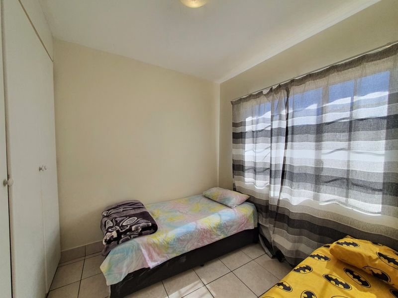 A functional bedroom featuring tiled flooring and a built-in wardrobe, providing essential storage space.