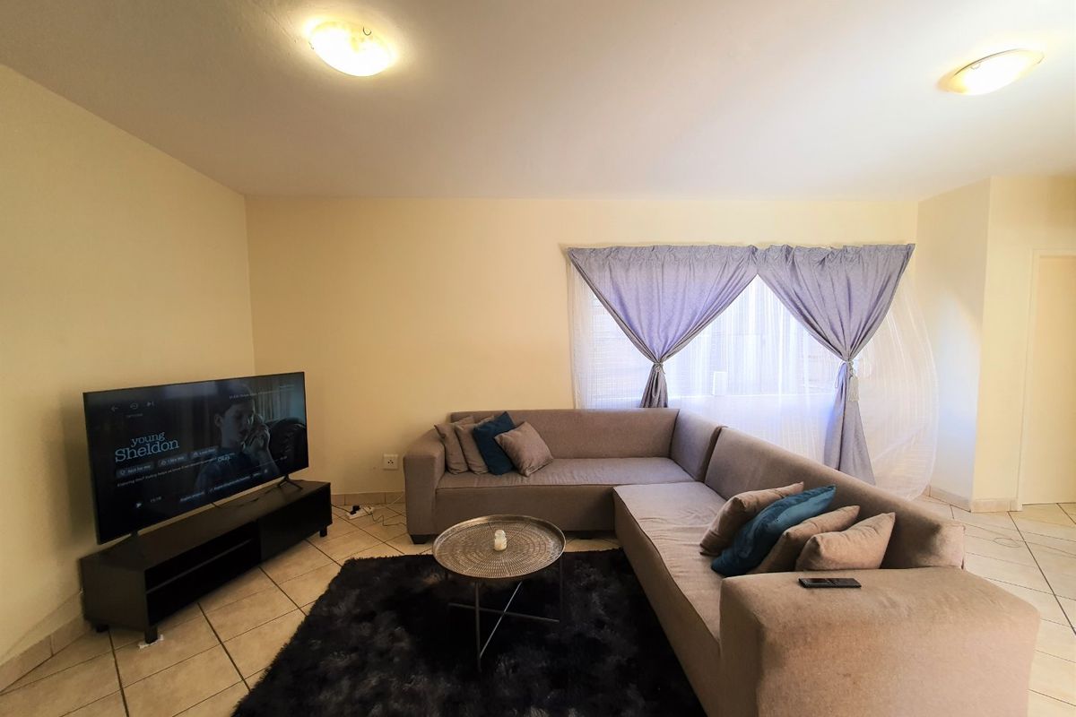 A comfortable living room featuring tiled flooring and neutral wall finishes, providing a functional space for relaxation.