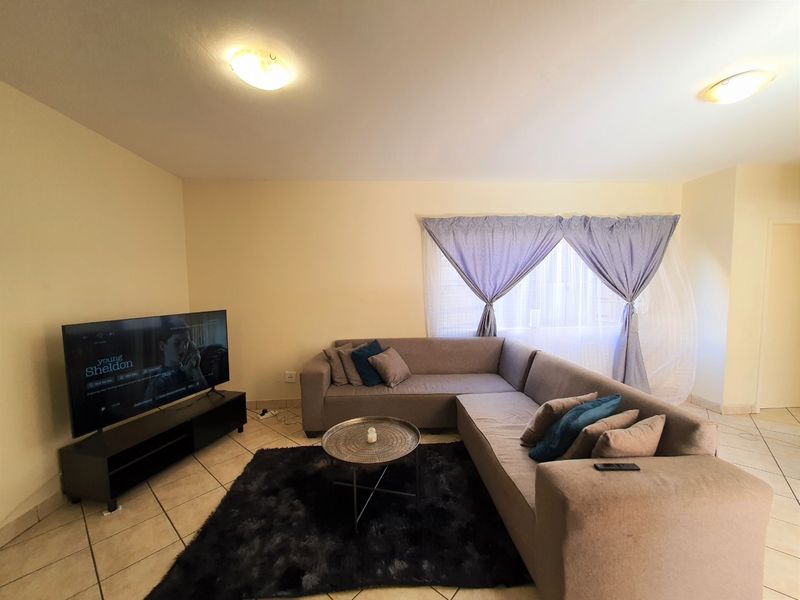 A comfortable living room featuring tiled flooring and neutral wall finishes, providing a functional space for relaxation.