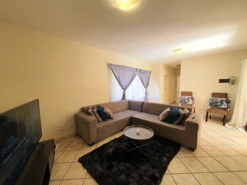 A functional living room featuring neutral tiled flooring and standard ceiling lighting, providing a comfortable and well-lit space for relaxation.