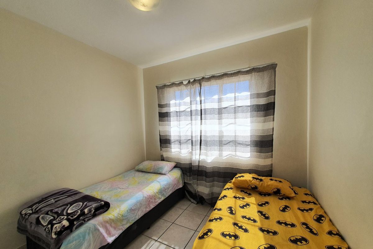 A compact bedroom featuring tiled flooring and a central ceiling light fixture, providing a functional space for sleeping.