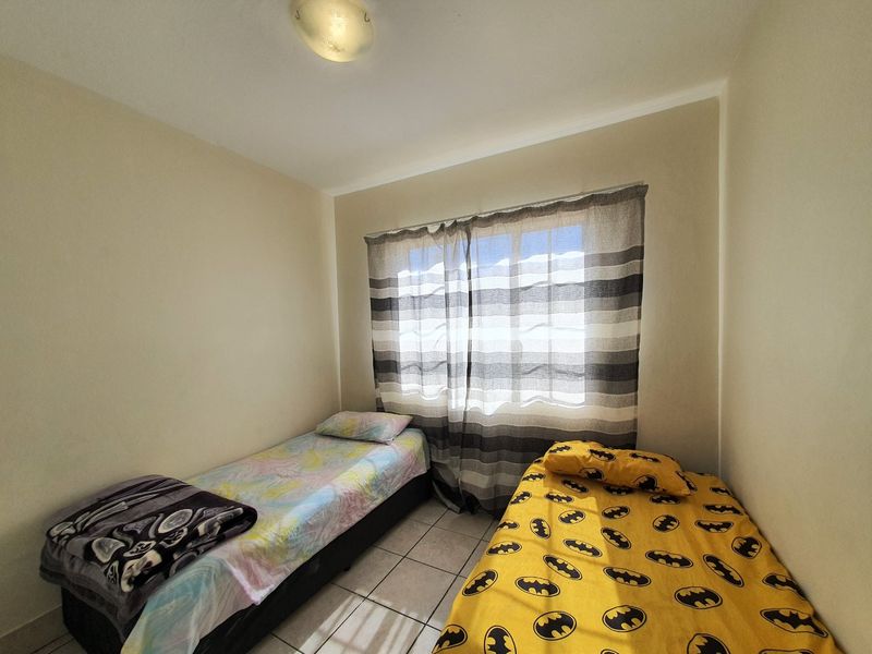 A compact bedroom featuring tiled flooring and a central ceiling light fixture, providing a functional space for sleeping.