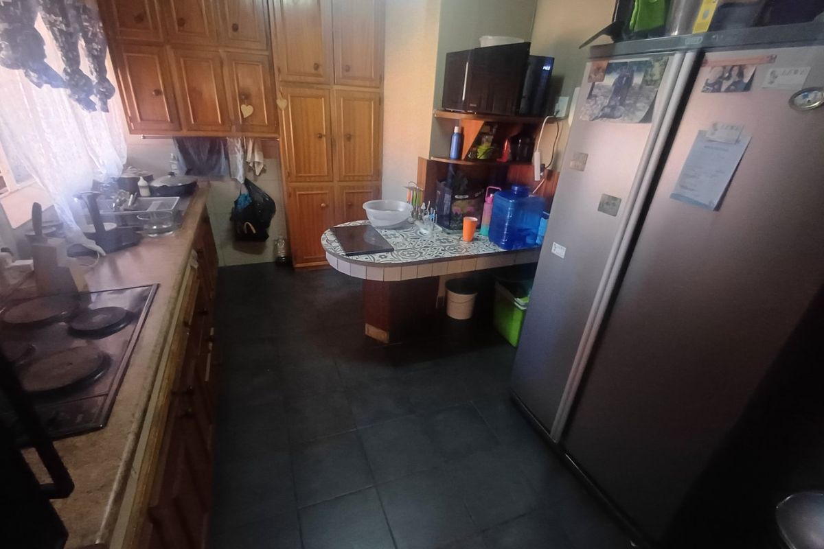 A functional kitchen featuring wooden cabinetry, a built-in hob, and a tiled breakfast nook, offering a practical layout for daily meal preparation.