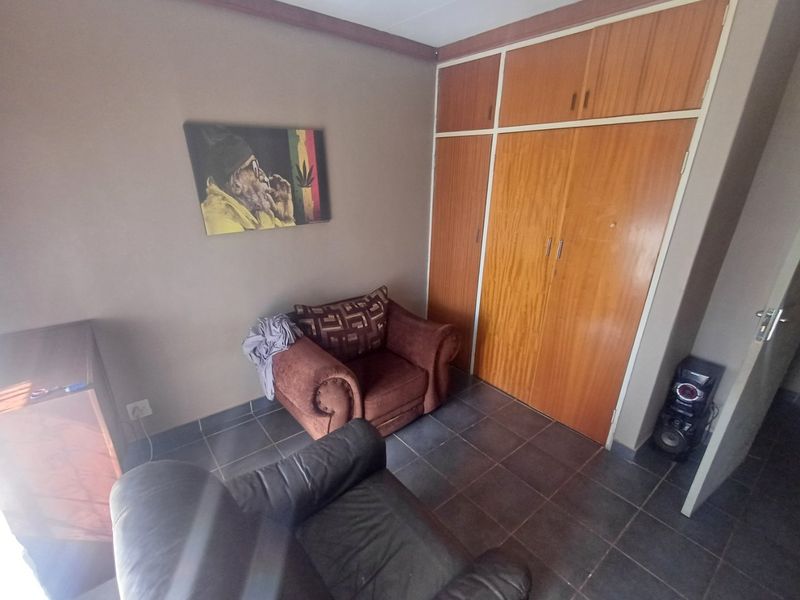 A bedroom featuring tiled flooring and built-in wooden cupboards providing ample storage space.