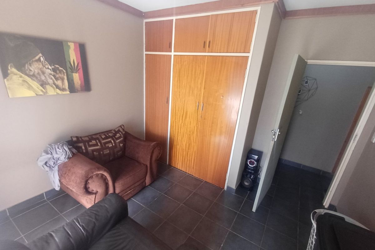A bedroom featuring built-in wooden cupboards, tiled flooring, and crown molding, offering a functional space with potential for cosmetic updates.