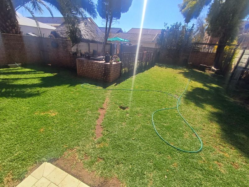 A private rear garden featuring a lawn area and a built-in brick braai, enclosed by perimeter boundary walls.
