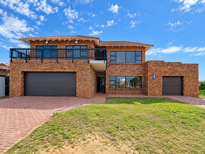 A well-maintained double-story face brick house featuring a paved driveway, a double garage, a single garage, and an upper-level balcony.