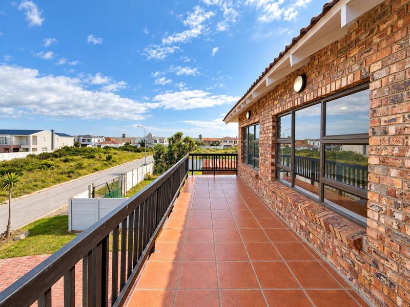 A spacious, tiled balcony featuring a brick exterior wall and a secure railing, offering an elevated outdoor space with neighbourhood views.
