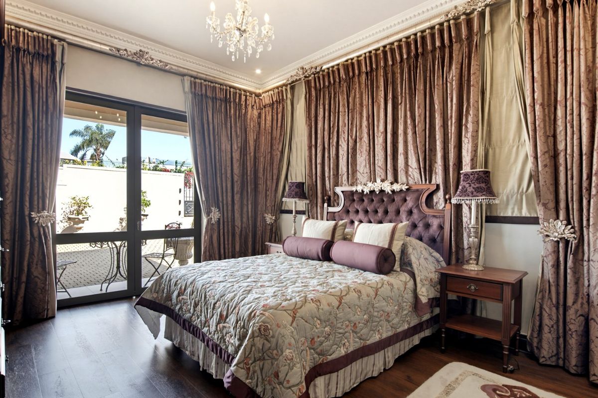 Spacious bedroom featuring hardwood flooring, elegant crown molding, and large sliding glass doors providing direct access to the outdoor patio area.