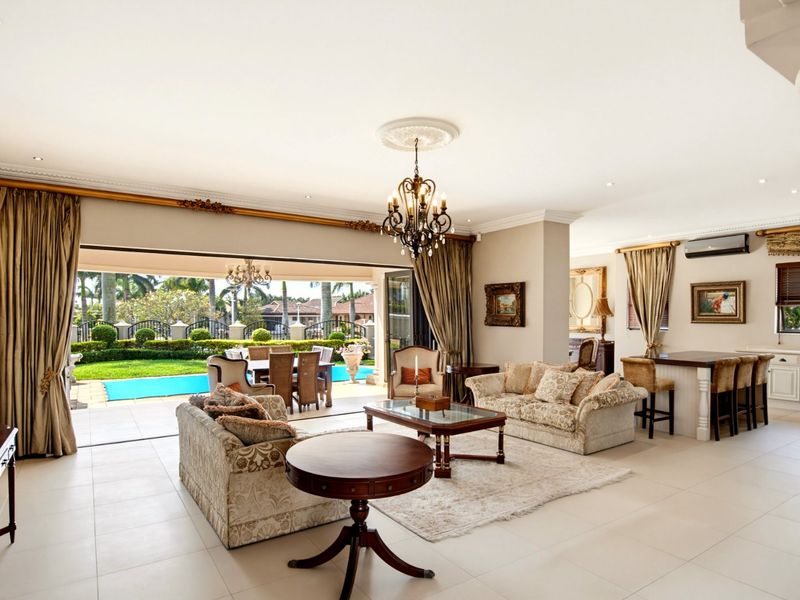 Spacious open-plan living area featuring tiled floors, elegant crown molding, and large sliding doors that open onto a patio and pool area.