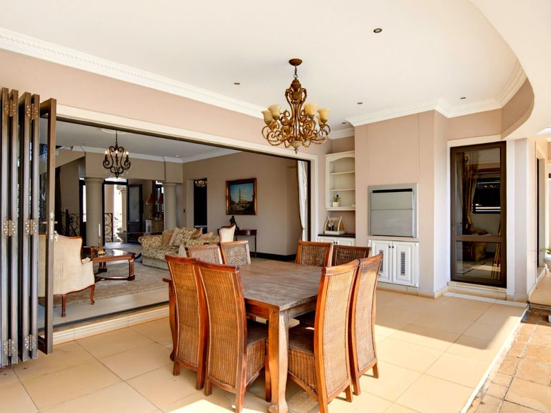 Covered patio featuring tiled flooring, a built-in braai, and large bi-fold doors that provide seamless access to the interior living area.