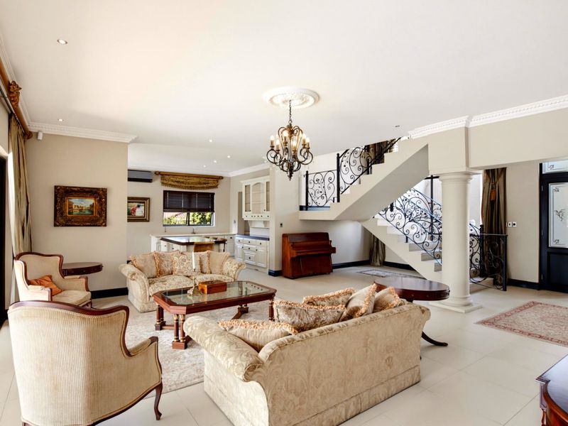 Spacious open-plan living area featuring a grand staircase with ornate wrought iron railings, tiled flooring, and elegant crown molding throughout.
