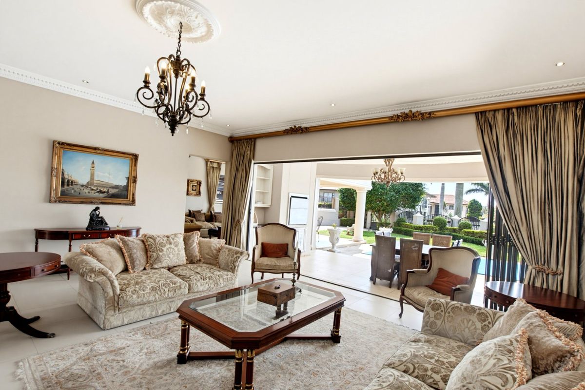 Spacious living room featuring elegant crown molding, a decorative ceiling rose, and large sliding doors that open onto a covered patio area.
