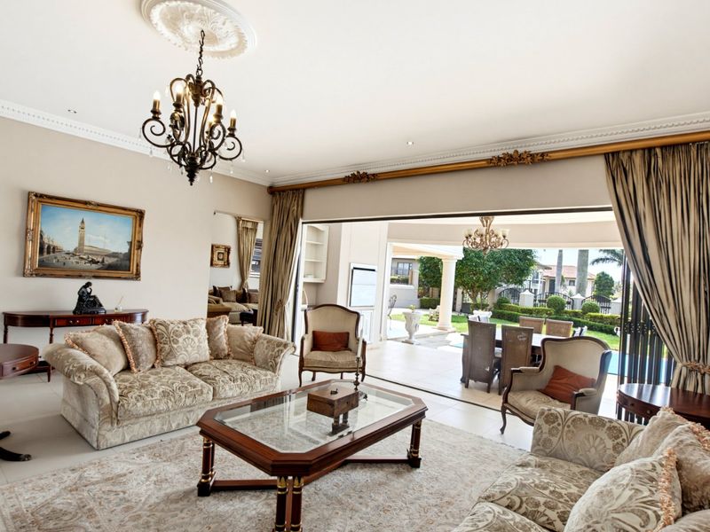 Spacious living room featuring elegant crown molding, a decorative ceiling rose, and large sliding doors that open onto a covered patio area.