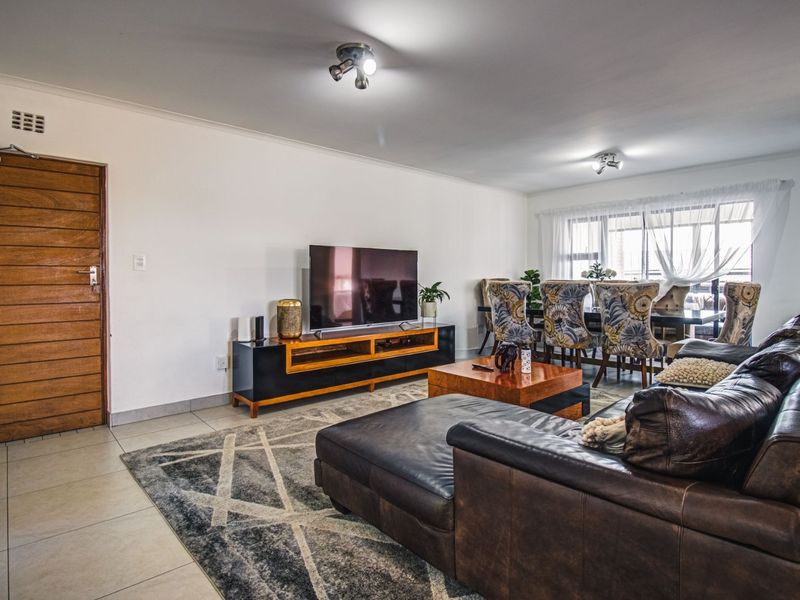 Spacious open-plan living and dining area featuring tiled flooring, neutral walls, and natural light from a large window.