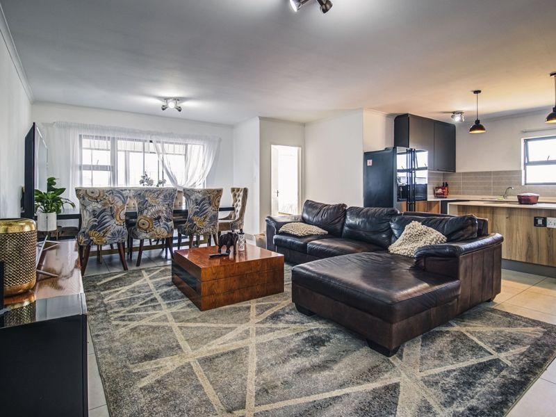 Spacious open-plan living and dining area featuring a modern kitchen with an island, tiled floors, and contemporary lighting throughout.