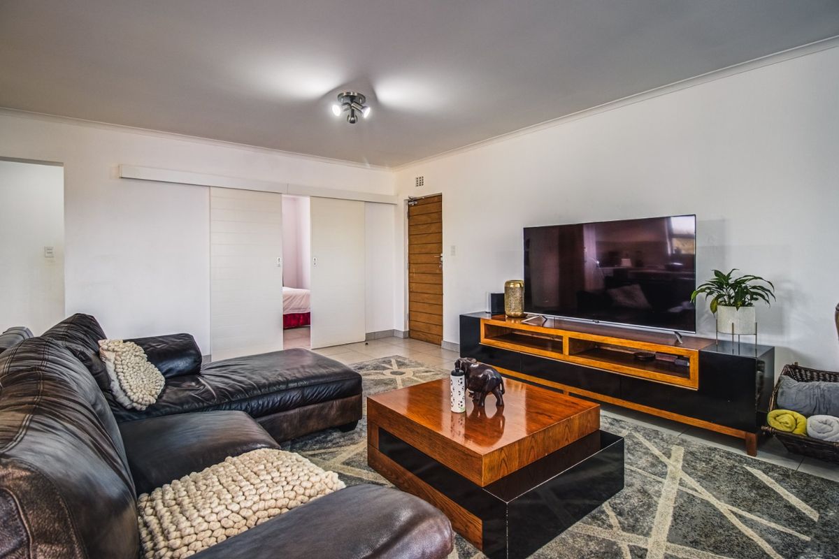 A well-maintained living room featuring tiled flooring, modern sliding doors, and neutral wall finishes, providing a comfortable and functional space.