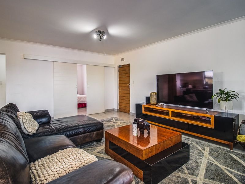 A well-maintained living room featuring tiled flooring, modern sliding doors, and neutral wall finishes, providing a comfortable and functional space.