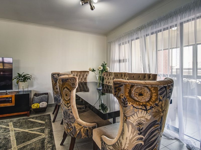 A well-lit dining area featuring tiled flooring and a large sliding glass door providing access to the balcony.