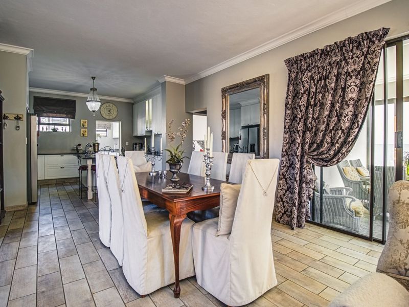Spacious open-plan dining and kitchen area featuring tiled flooring, modern cabinetry, and large sliding glass doors providing access to the outdoor patio.