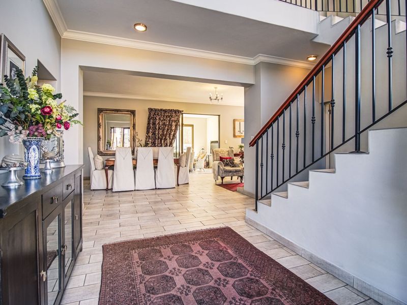 Spacious entrance hall featuring tiled flooring, a staircase with a wrought iron balustrade, and an open-plan flow into the dining area.