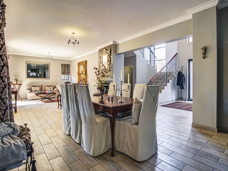 Spacious open-plan living and dining area featuring tiled floors, a fireplace, and an elegant staircase leading to the upper level.